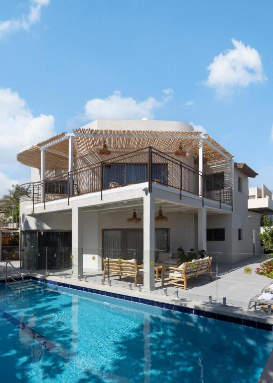 a villa with a swimming pool and a house at Ella Sun - Coconut Villa in Eilat