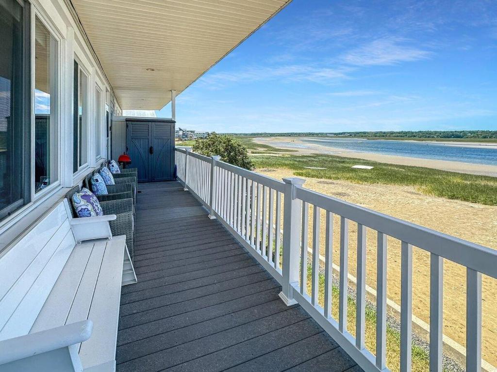 a porch of a house with benches on the beach at Admiral's Quarters in Wells Beach