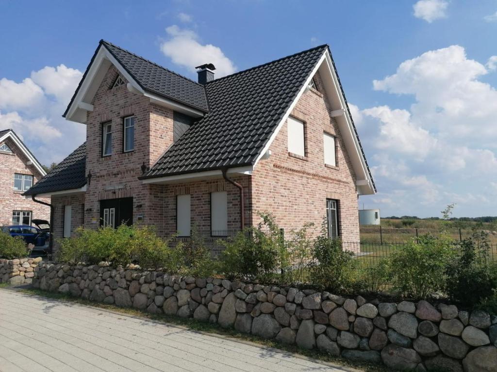 ein Backsteinhaus mit einem schwarzen Dach und einer Steinmauer in der Unterkunft Ferienhaus Treibholz in Hof Barendorf