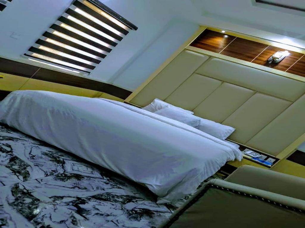 a bedroom with a bed with white sheets and a window at Victoria Garden Hotel & Fast Food Service in Onitsha