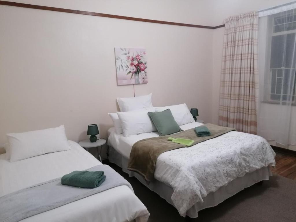 a bedroom with two beds with white sheets and a window at Agape Gastehuis in Jagersfontein
