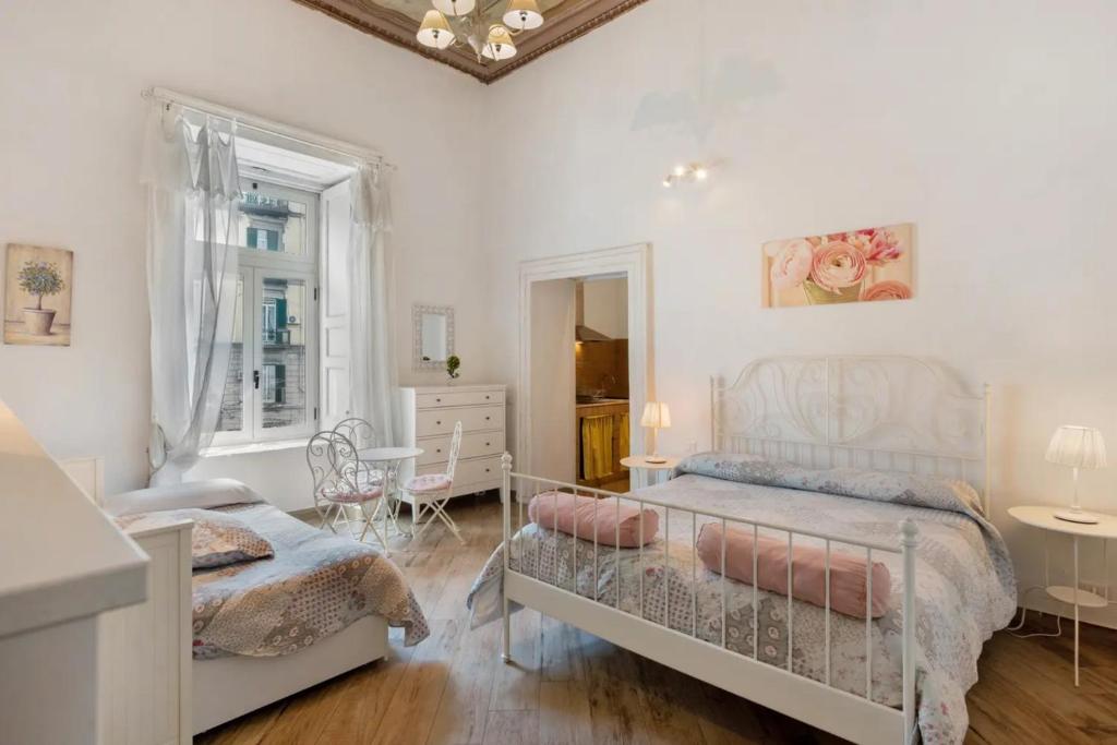 a white bedroom with a bed and a table at Aparthotel in pieno centro storico in Naples