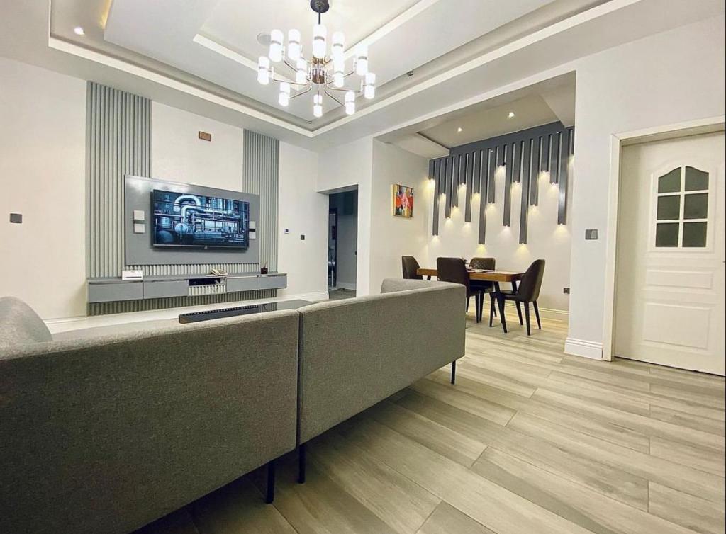 a living room with a couch and a television on a wall at Zilla Luxury - Lifecamp in Abuja