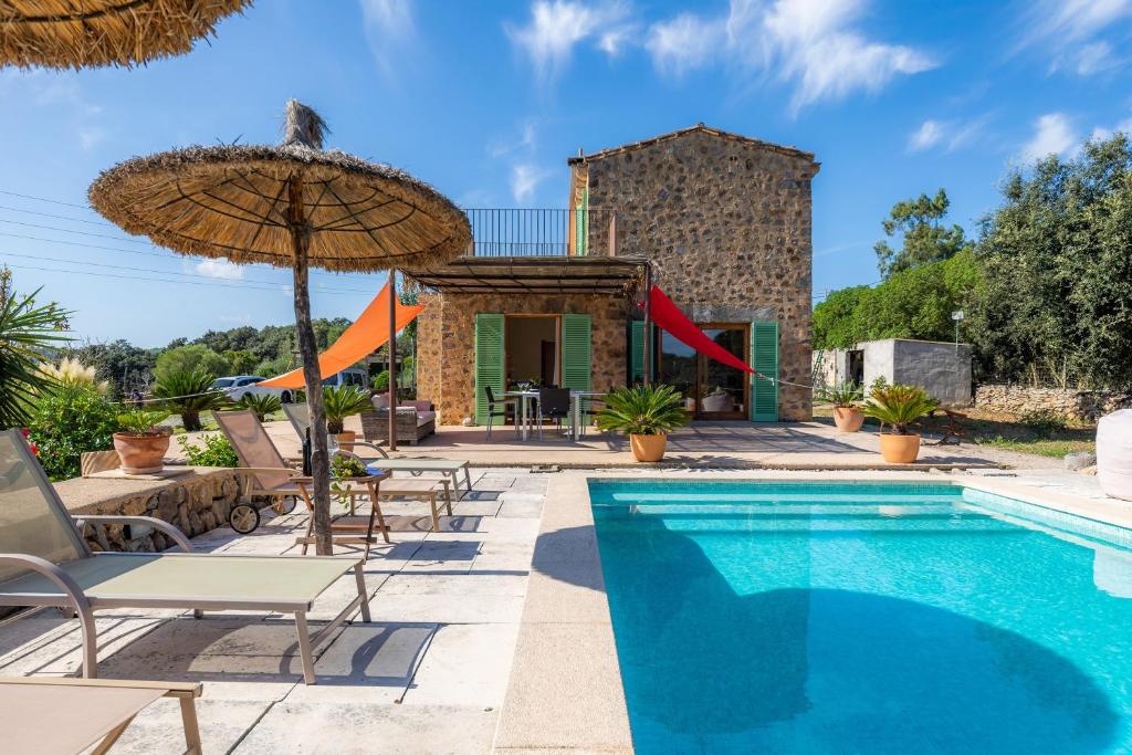 een zwembad met stoelen en een parasol naast een huis bij Son Frare in Artá