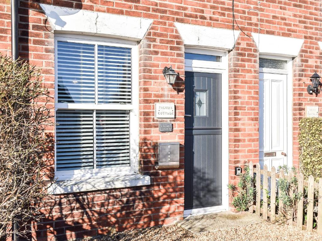 een bakstenen huis met een zwarte deur en ramen bij Fuchsia Cottage in Sea Palling