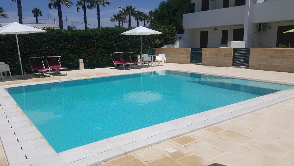 een groot blauw zwembad met stoelen en parasols bij Villa piscina 24 posti letto in Torre dell'Orso