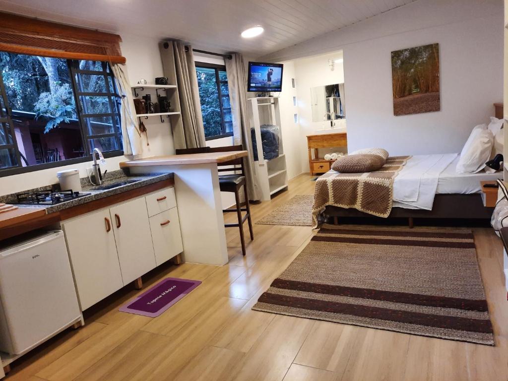 a kitchen and living room with a bed in a room at Refúgio na natureza Casa do Tecelão in Curitiba