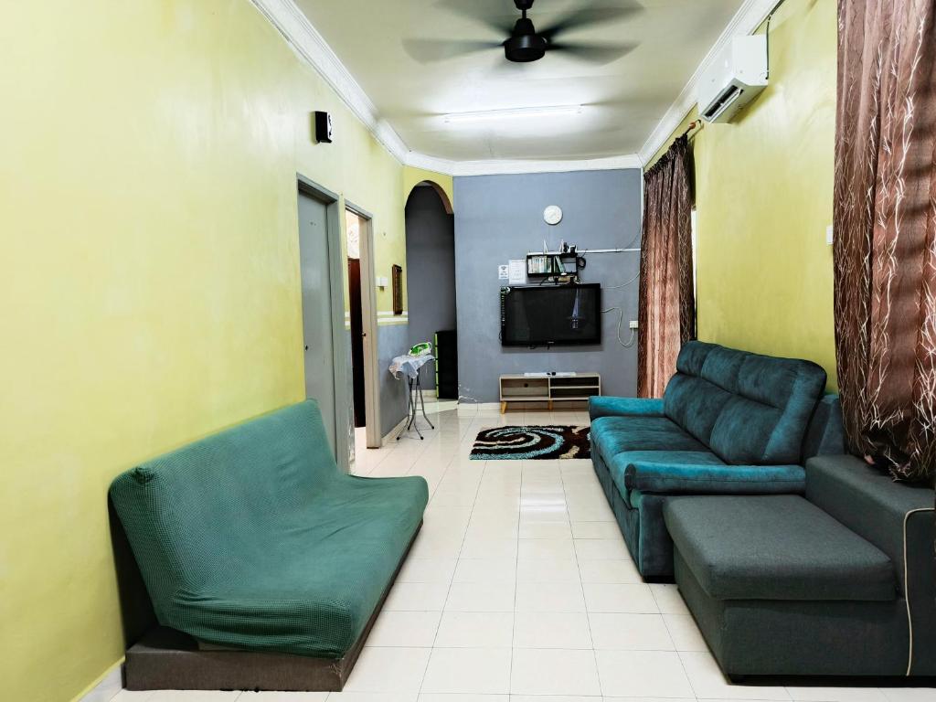a living room with a couch and a tv at RIZQI HOMESTAY Sungai Siput with Wifi! Islamic Guest Only! in Kampong Rimba Panjang