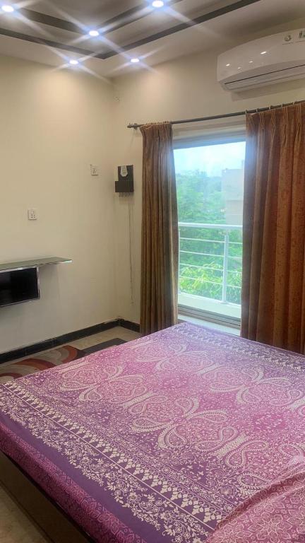 a bedroom with a purple bed with a window at Iqbal's Den in Multan