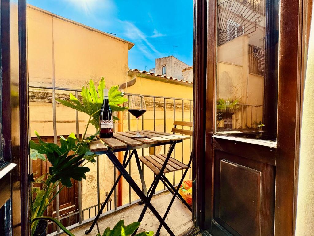 シラクーサにあるCasa Artemis nel cuore di Ortigia a Siracusaのバルコニーにテーブルとワイン2杯