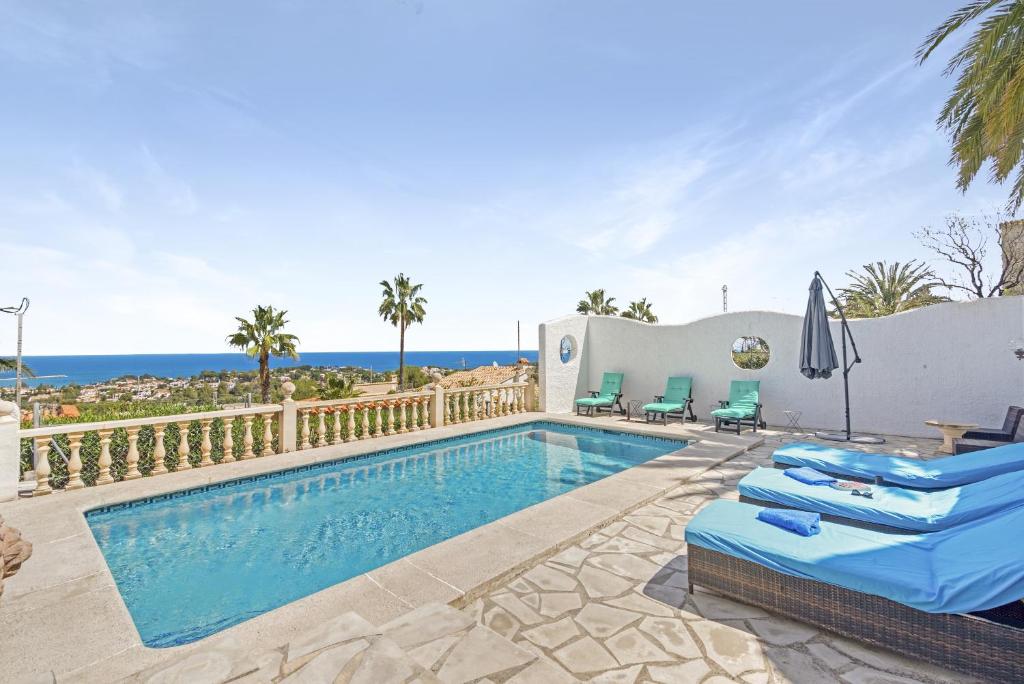 a pool with chairs and an umbrella and the ocean at Adriana in Denia