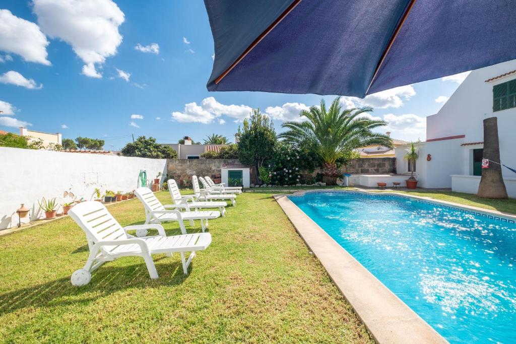 eine Gruppe weißer Stühle neben einem Pool in der Unterkunft Villa en Son Gall Ciutadella in Ciutadella