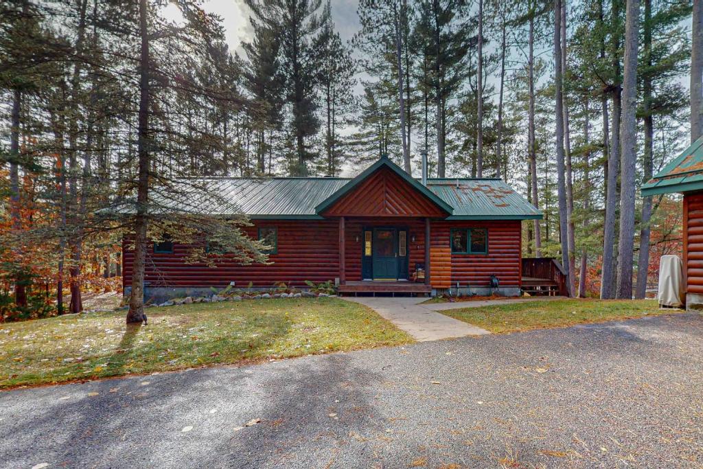 a small log cabin with a porch in the woods at Camp Farrell in Manitowish Waters
