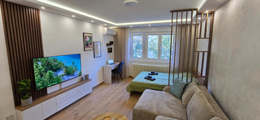 Una sala de estar con un sofá y un televisor de pantalla plana. en Leaf & Loft, en Novi Sad