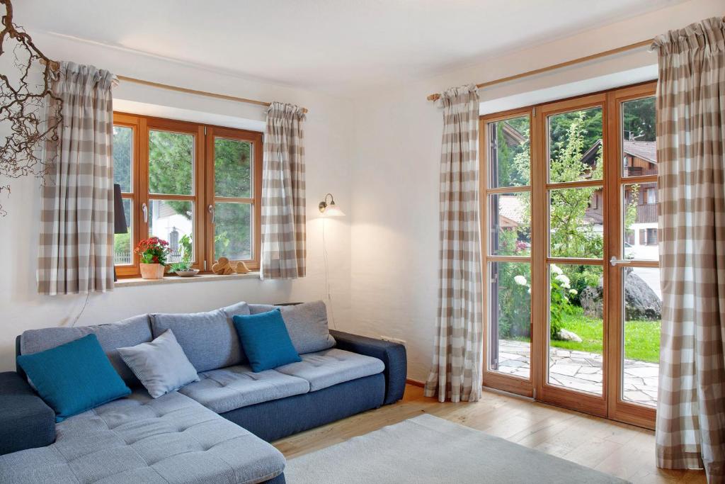 a living room with a blue couch and windows at Ferienwohnung Zugspitzblick in Grainau