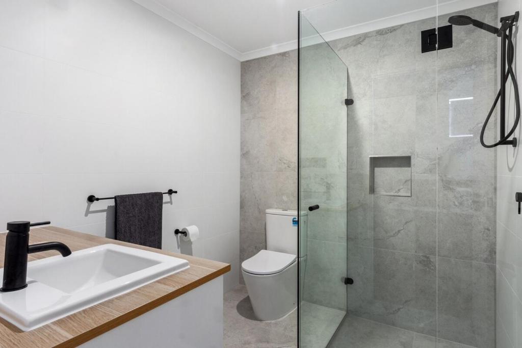 a bathroom with a shower with a sink and a toilet at Charming 1-Bed Coastal Escape at Links Lady Bay in Normanville
