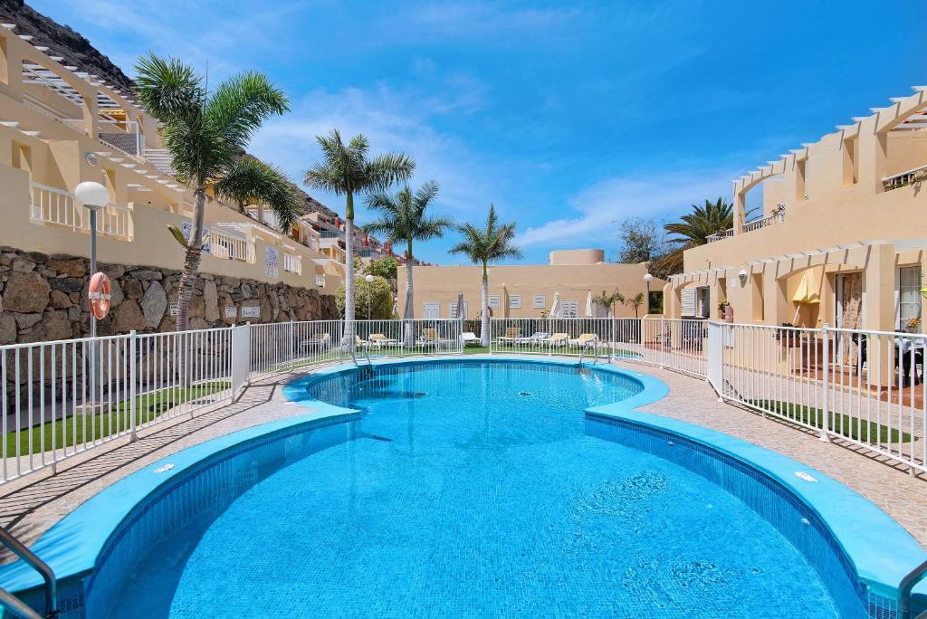a swimming pool in a resort with palm trees and buildings at Mangueros Suite 18 Puerto de Mogán in Puerto de Mogán
