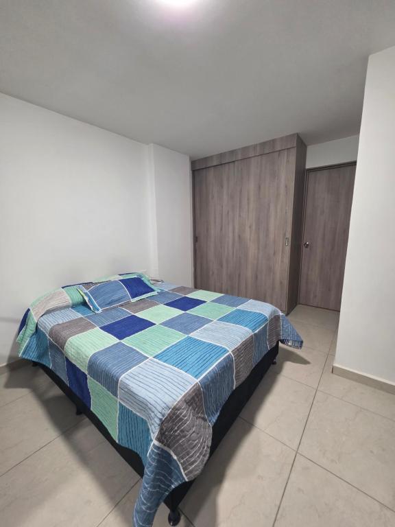 a bedroom with a bed with a blue checkered blanket at Apartaestudio 101 cómodo y Moderno in Tuluá