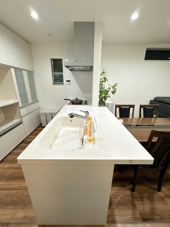 a white kitchen with a sink and a table at Kasilin House in Osaka