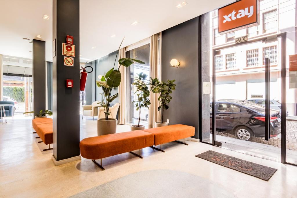 un vestíbulo con bancos naranjas y un concesionario de coches en Xtay Cais Rooftop - Studio completo com vista panorâmica Skyglass Tetto - Orla do Guaíba, en Porto Alegre