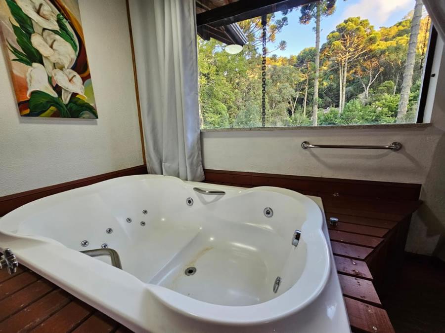 uma banheira branca em um banheiro com janela em Pousada Bramasole em Monte Verde