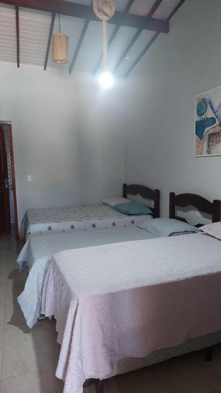 two beds in a room with white walls at Casa Pé na Areia in Barra Grande