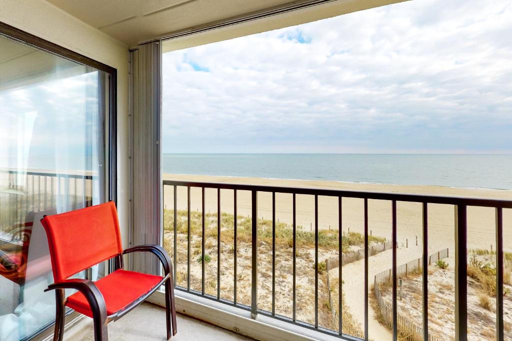 a red chair sitting on a balcony looking out at the beach at Waikiki #302 in Ocean City