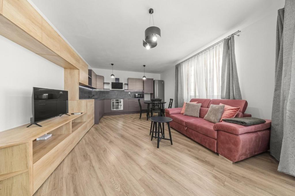 ein Wohnzimmer mit einem roten Sofa und einem TV in der Unterkunft Air-conditioned 2-bedroom apartment, balcony, Závadská-Rača in Rača