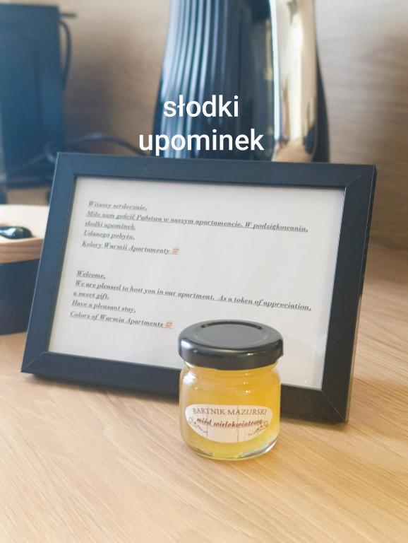 a jar of stickyumpumpump inhibitor next to a framed picture at Kolory Warmii Apartamenty Biały i Szary in Olsztyn