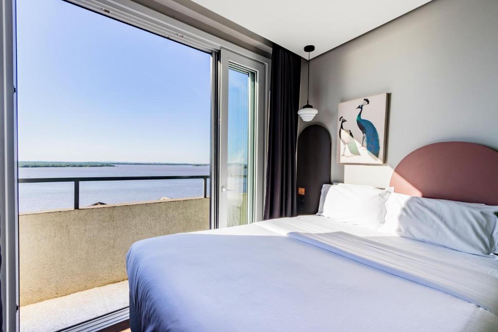 Postel nebo postele na pokoji v ubytování Xtay Cais Rooftop - Studio completo com vista panorâmica Skyglass Tetto - Orla do Guaíba