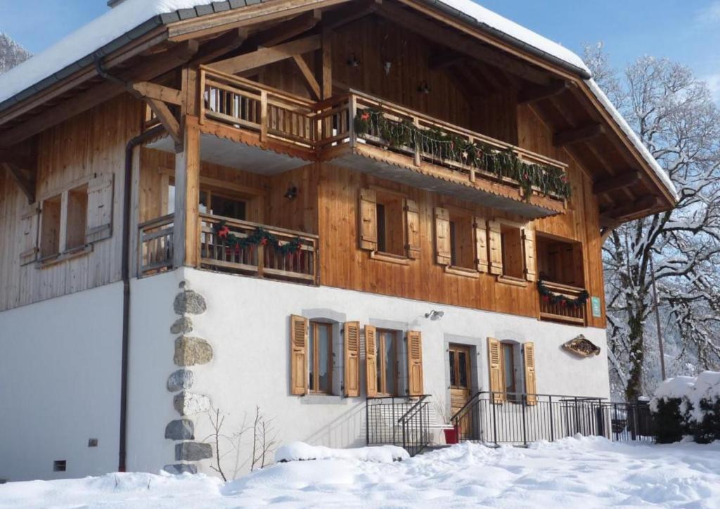 a wooden house with a balcony in the snow at Ferme Le Coup d'Oeil in Taninges