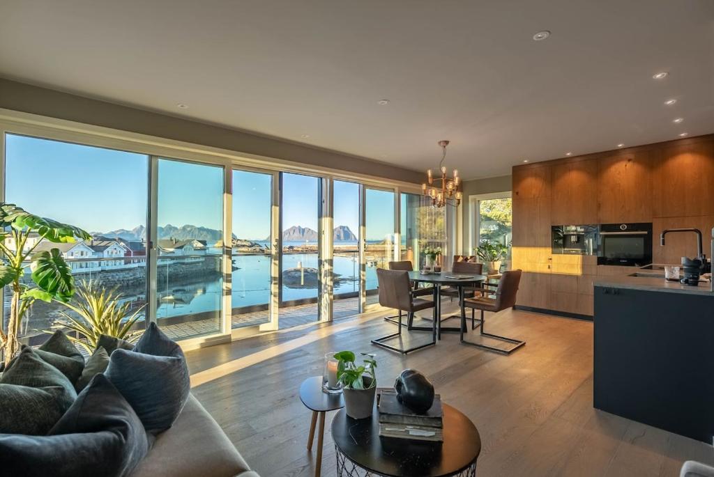 Una sala de estar con un sofá y una mesa y una cocina. en Lofoten Oceanfront Panoramic, en Kabelvåg