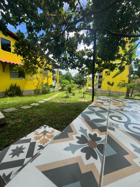 a garden with a patterned floor in front of a yellow building at Ilha de Boipeba Casa com 2 quartos com ar condicionado no 1ºandar in Cayru