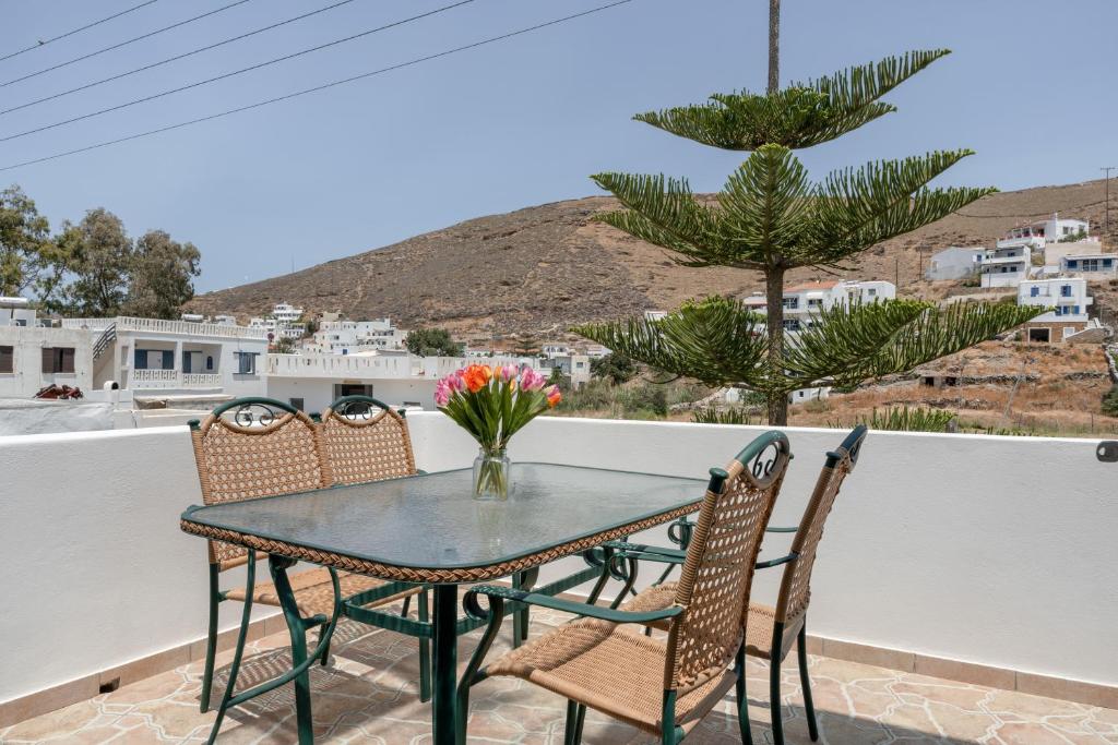 a table with chairs and a vase of flowers on a balcony at Mouria House in Kithnos