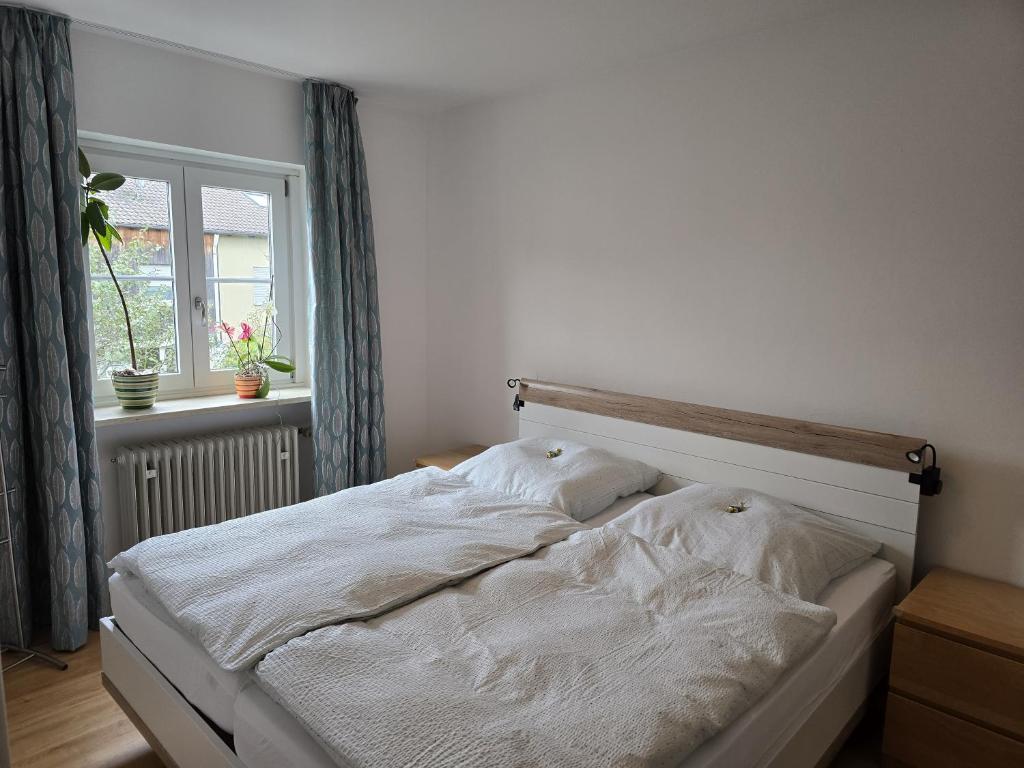 Una cama blanca en un dormitorio con ventana. en Charmantes Haus mit eigenem Garten, en Prien am Chiemsee