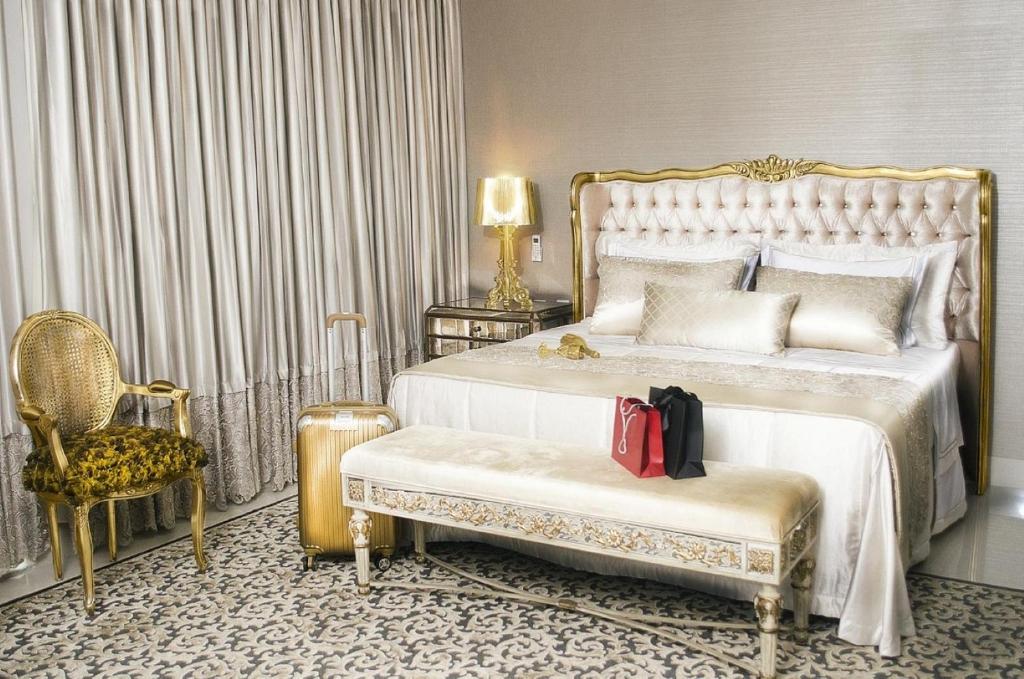 a bedroom with a large bed and a chair at CEU PALMAS Hotel in Palmas