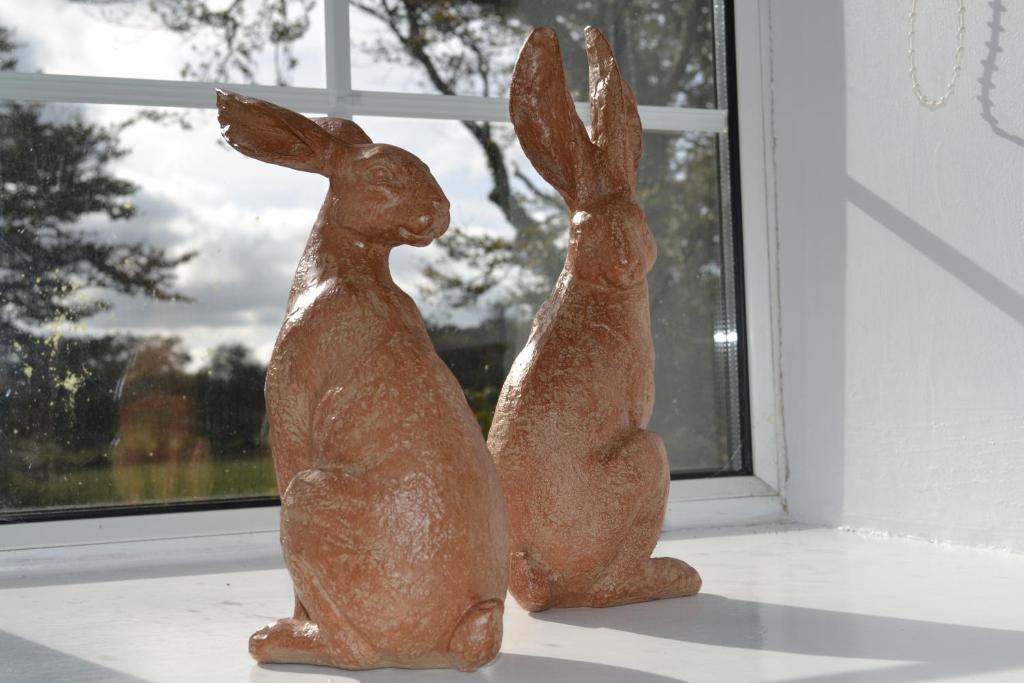 two statues of rabbits sitting on a window sill at CherryBrook Wistman Suite in Two Bridges