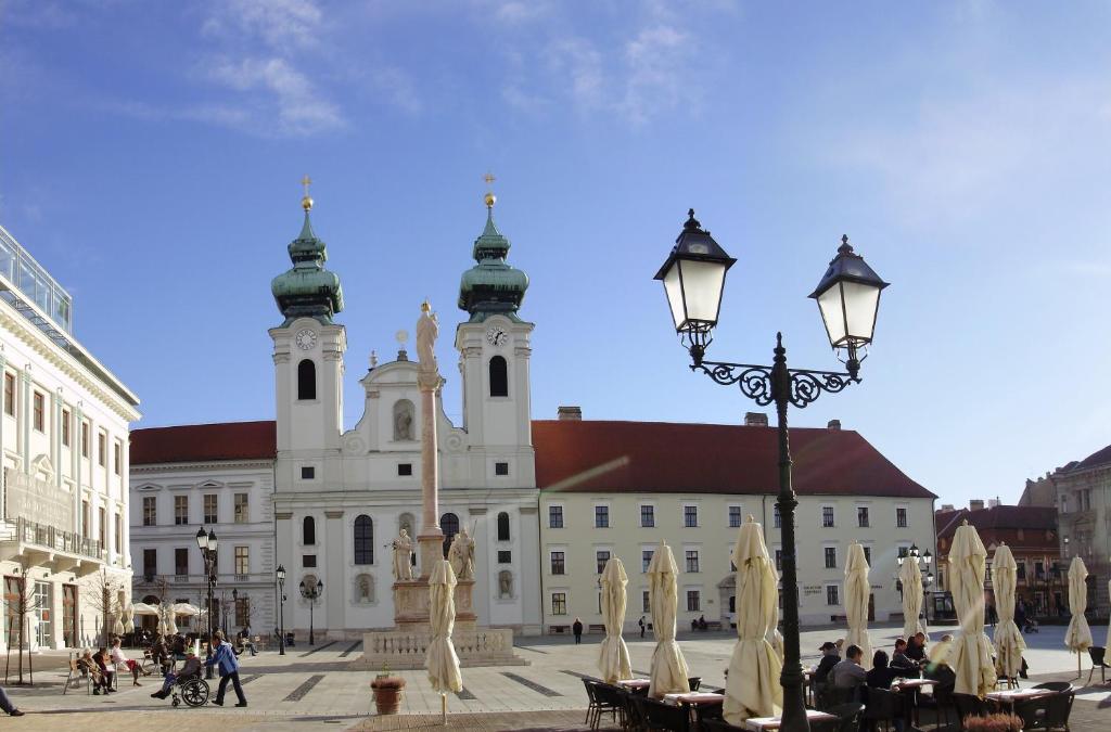 duży biały budynek z dwoma wieżami i światłem ulicznym w obiekcie Duett - Urban Rooms w Győr