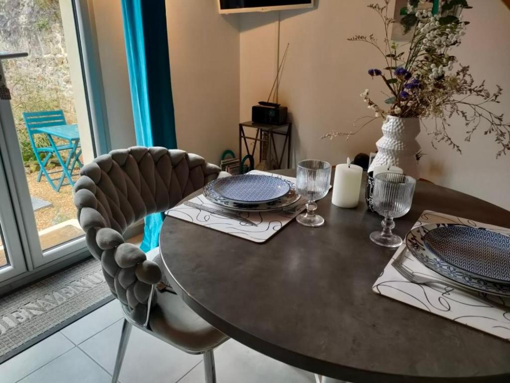 a dining room table with two chairs and a table with plates at La Suite 27 bis, maison indépendante avec terrasse, proche gare et centre in Guingamp