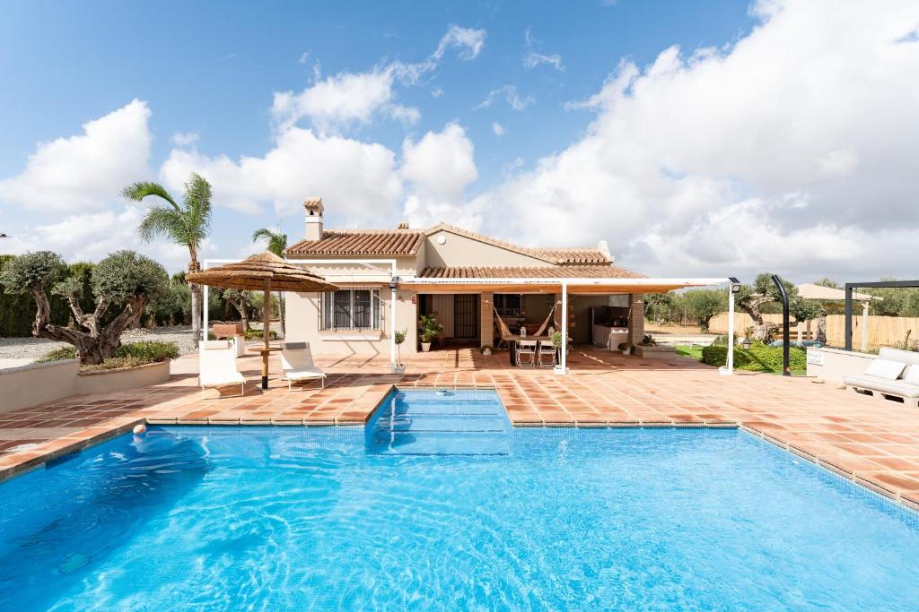 a villa with a swimming pool and a house at Villa tranquila el retiro in Málaga