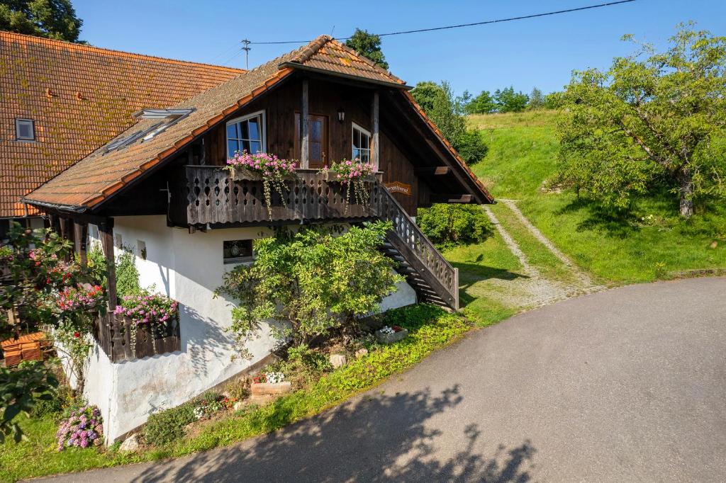 a house with a balcony with flowers on it at Schwarzwald Buchenhof in Zell am Harmersbach