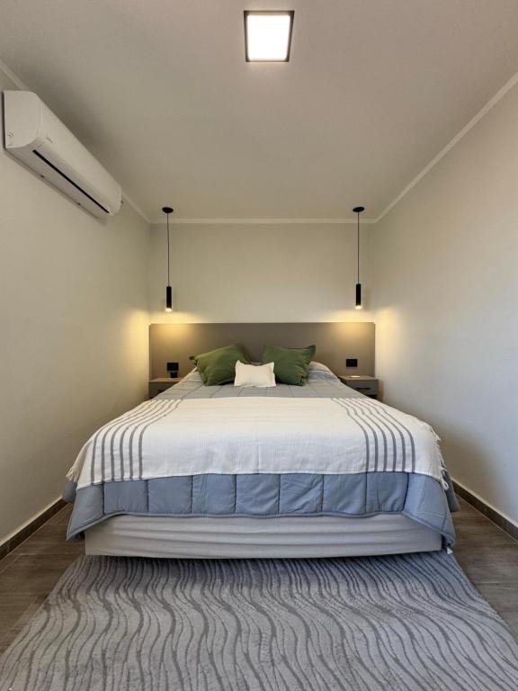 Un dormitorio con una cama grande con almohadas verdes. en 250 Deptos Temporarios, en San Fernando del Valle de Catamarca