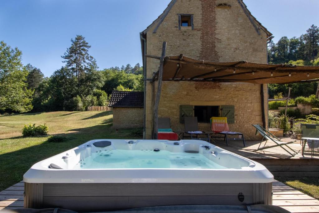 a hot tub in the yard of a house at Moulin au coeur de la nature in Thonac