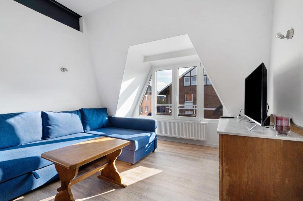 a living room with a blue couch and a tv at Die Alter Schwede Wohnung 2 in Vechta