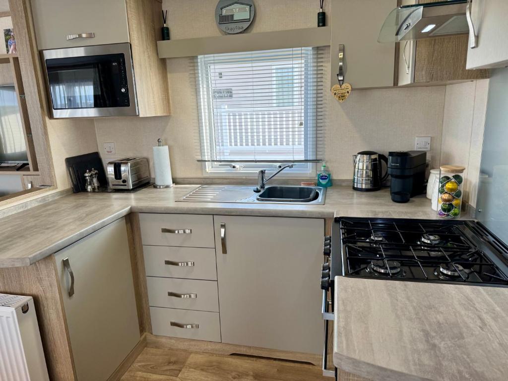 eine kleine Küche mit Spüle und Herd in der Unterkunft Sutherland C14 in Lossiemouth