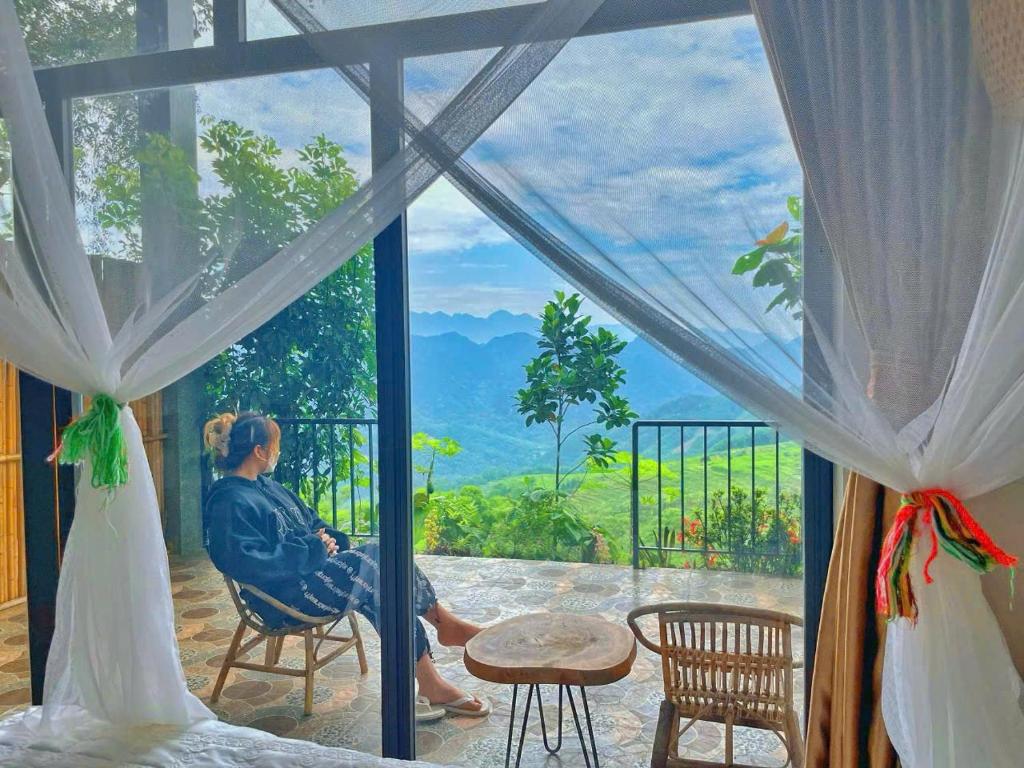 um homem e uma mulher sentados na varanda olhando pela janela em Mai Hill Homestay em Ải Hạ