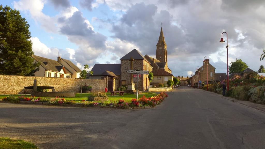 an empty street in a small town with a church at French Village Living in Saint-Fraimbault