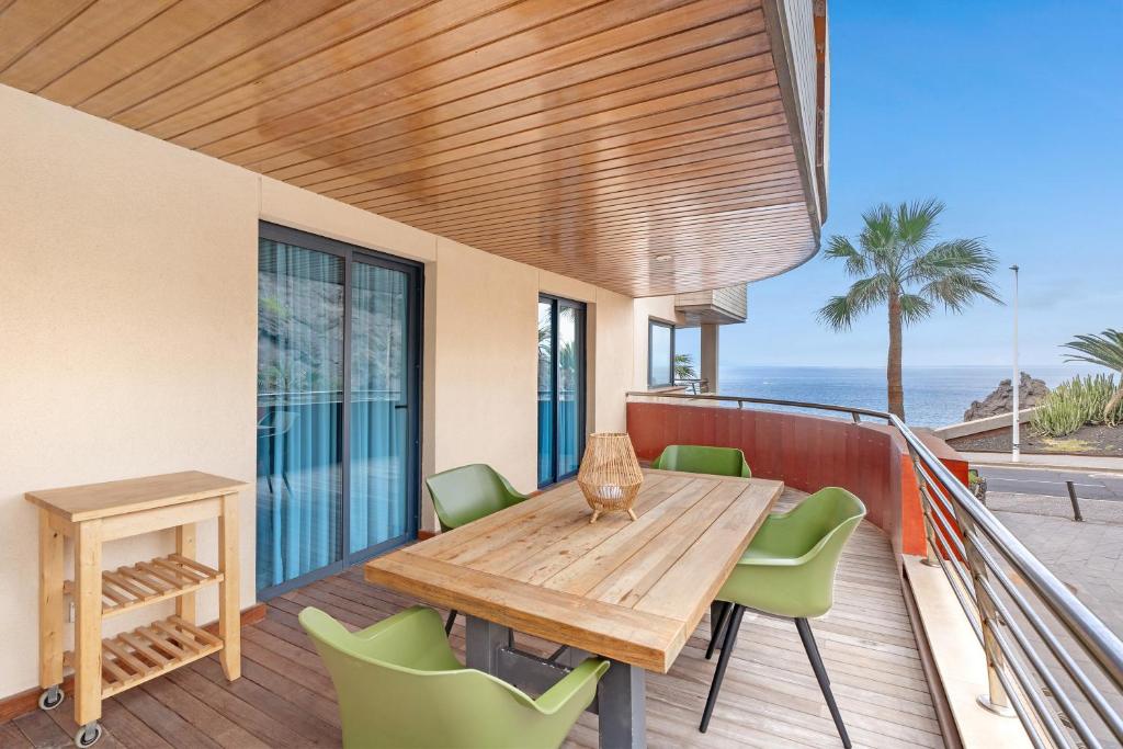 a wooden table and chairs on a balcony with the ocean at Balcón de Los Gigantes in Puerto de Santiago