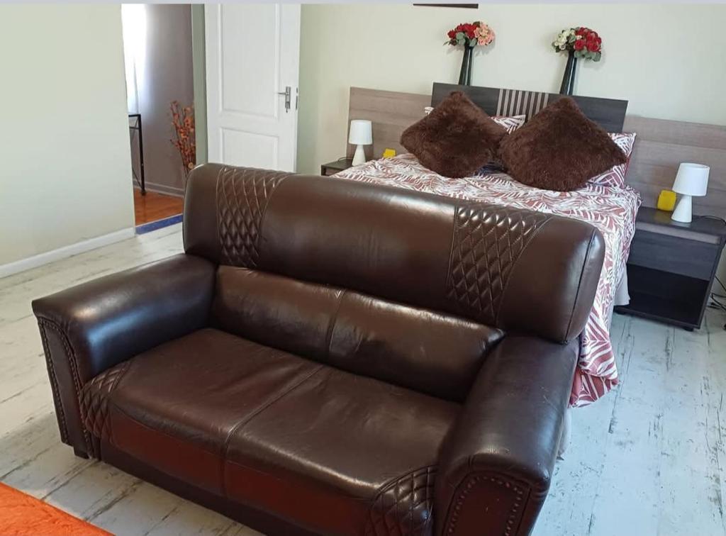 een bruine leren bank voor een bed bij Serene on 5 Cologne in Germiston