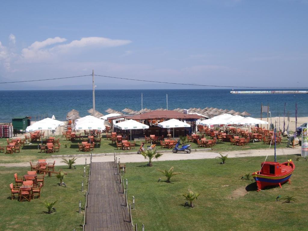 a restaurant with tables and chairs on the beach at Mare Beach Apartments in Stavros